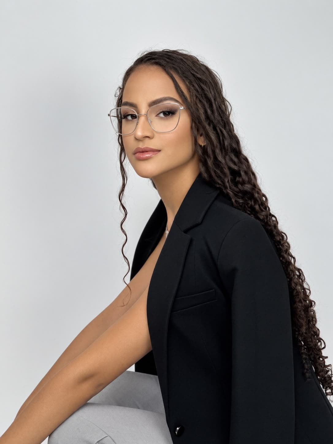 Retrato de Luiza Pego, biomédica esteta, de perfil, com blazer preto e óculos
